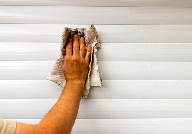 person-cleaning-a-white-garage-door